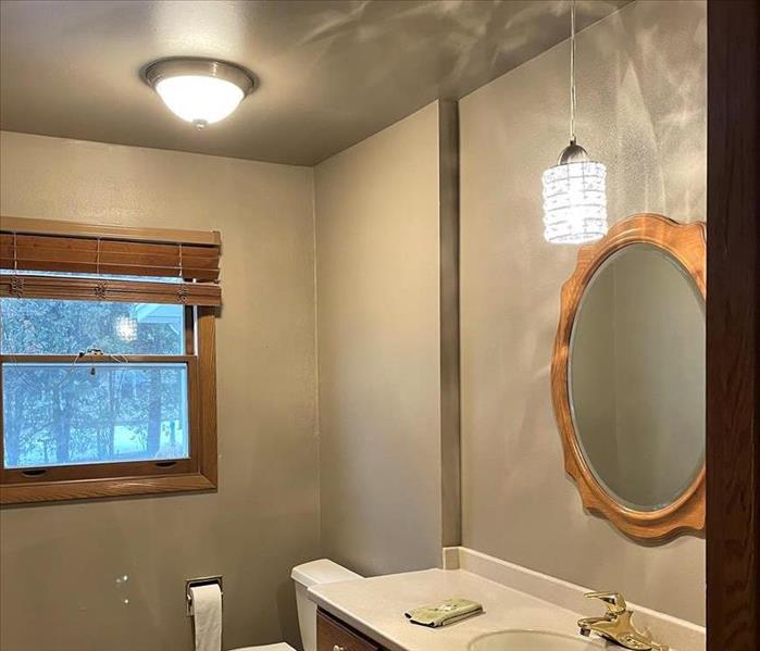 a newly repaired bathroom with new drywall and neutral paint after having water damage