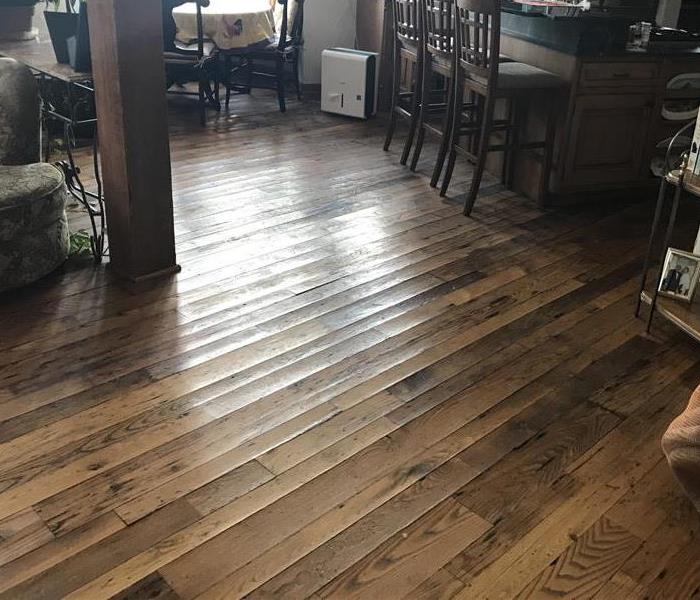 water damaged cupped wood floors in a family room that runs into part of a kitchen