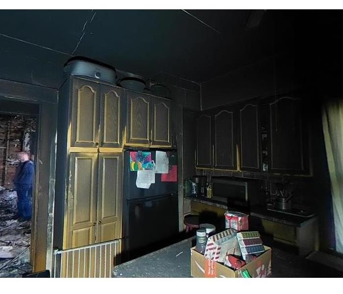 a kitchen with charred cabinets and walls from fire damage