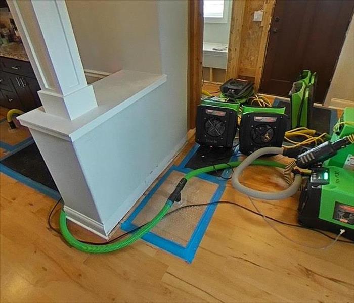multiple air movers with SERVPRO floor mat system drying a water damaged hardwood floor