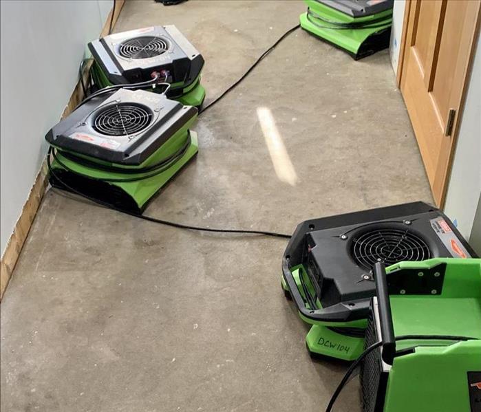 hallway with multiple servpro green airmovers and dehumidifiers to dry a water damaged space