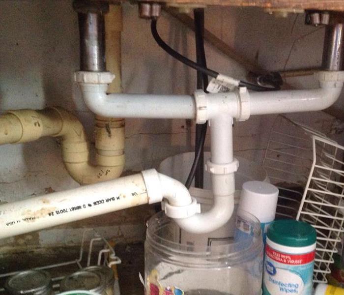 water pipes under a cabinet as the cause of water damage to kitchen 