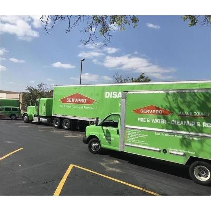 large green semi truck, box truck, and various other green SERVPRO trucks on site for a storm response