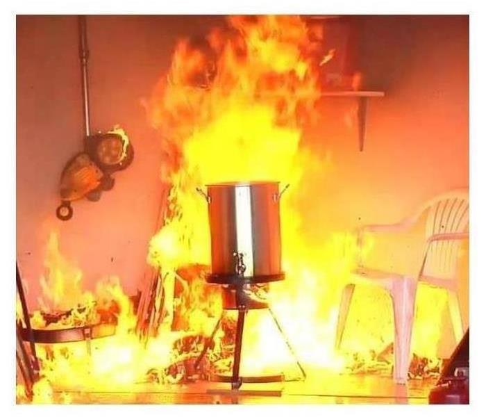 a turkey deep fryer on fire with chairs melting and also on fire around it