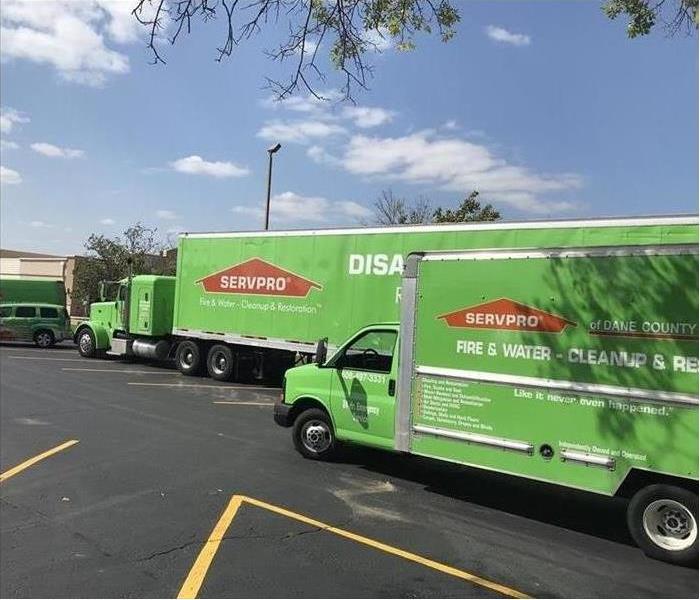 large green semi truck, box truck, and various other green SERVPRO trucks on site for a storm response
