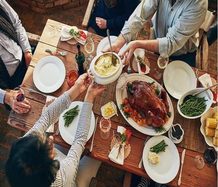 a holiday dinner with a turkey, stuffing, etc., and many people toasting 