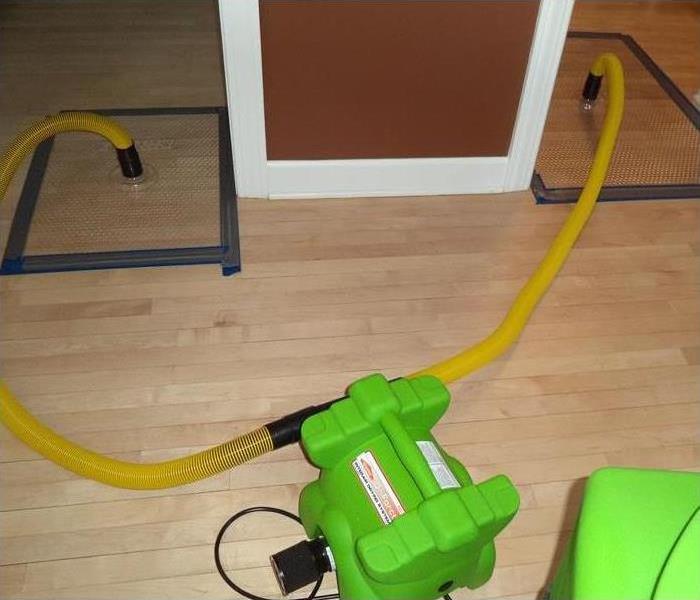 a wood floor with servpro floor mat drying system in use